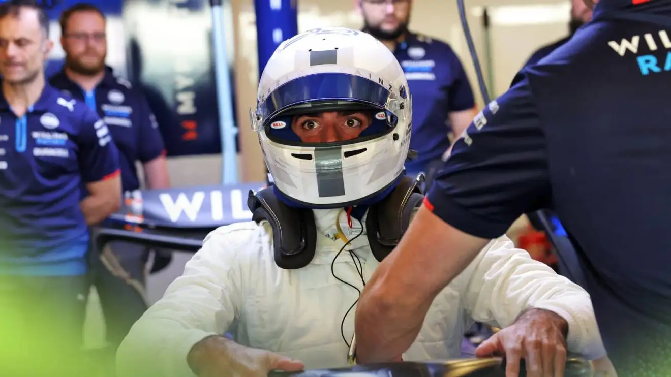 c-771 Carlos Sainz's eyes are visible through his open visor as he climbs out of the car in the Williams garage