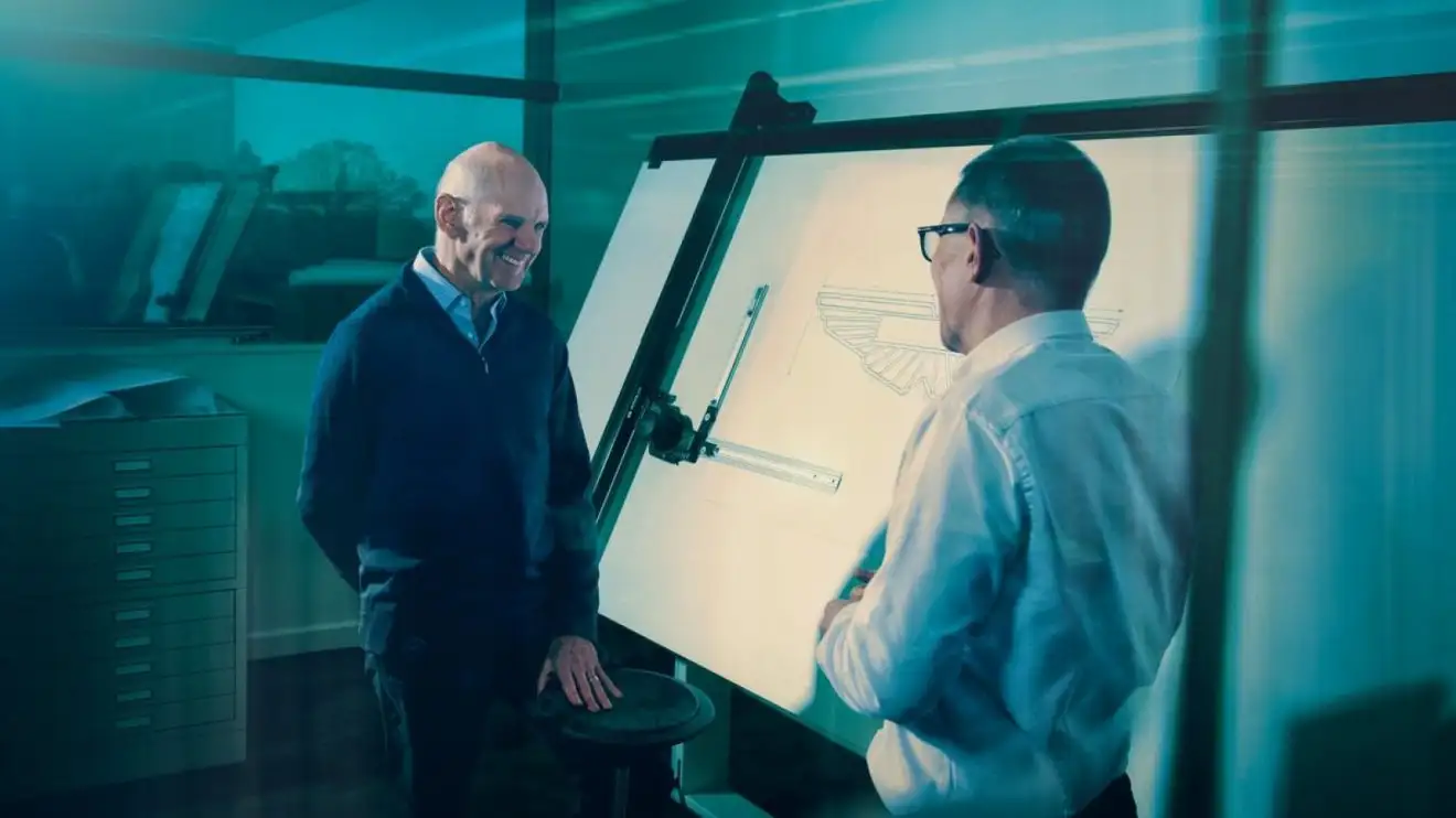 Adrian Newey smiles while standing alongside a drawing board in his new Aston Martin office