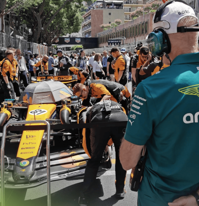 A rear-facing shot of Adrian Newey studying the McLaren MCL39 on the grid in Monaco