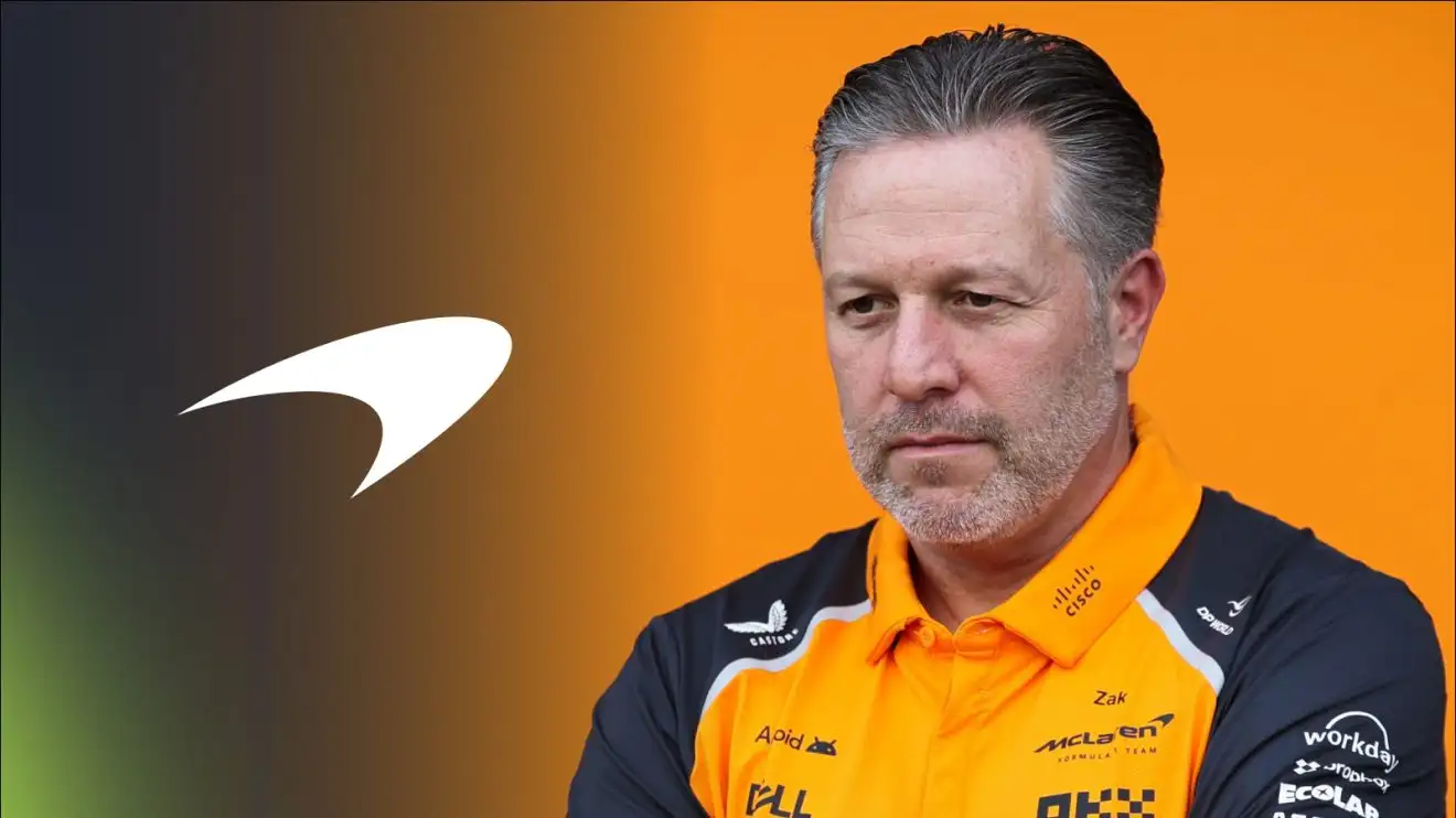 A stern-looking Zak Brown stares into the distance outside McLaren's garage.