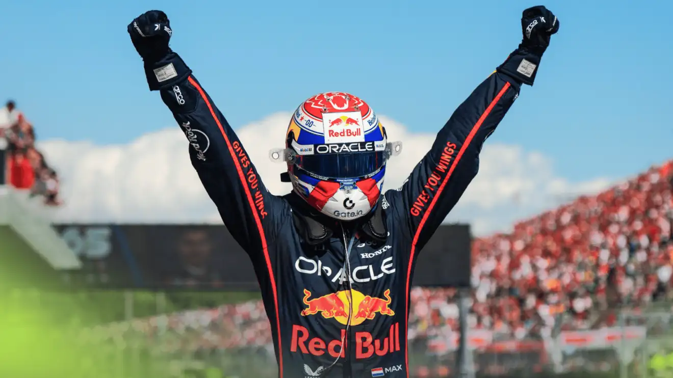 c-1260 Max Verstappen raises both fists in celebration in parc ferme at Imola with a blue sky in the backdrop