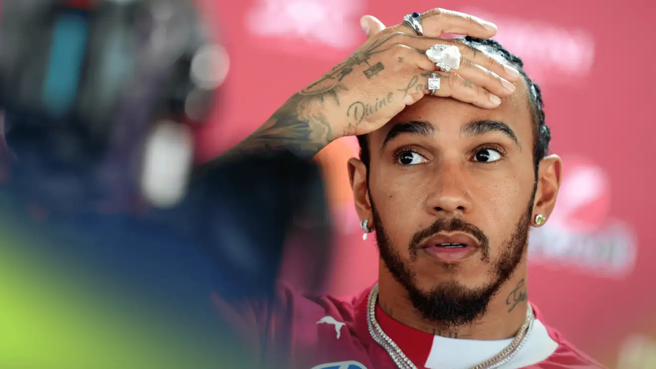 c-1729 Lewis Hamilton holds his hand to his head while facing the media