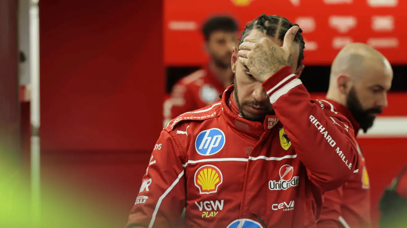 c-348 Lewis Hamilton holds his hand to his head as he walks through the Ferrari garage