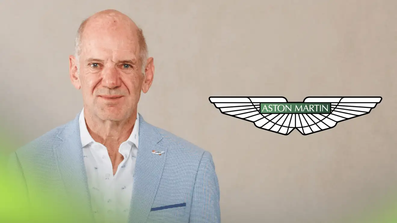 c-722 Adrian Newey wearing a suit on his first official image as an Aston Martin signing with a prominent Aston Martin logo alongside him