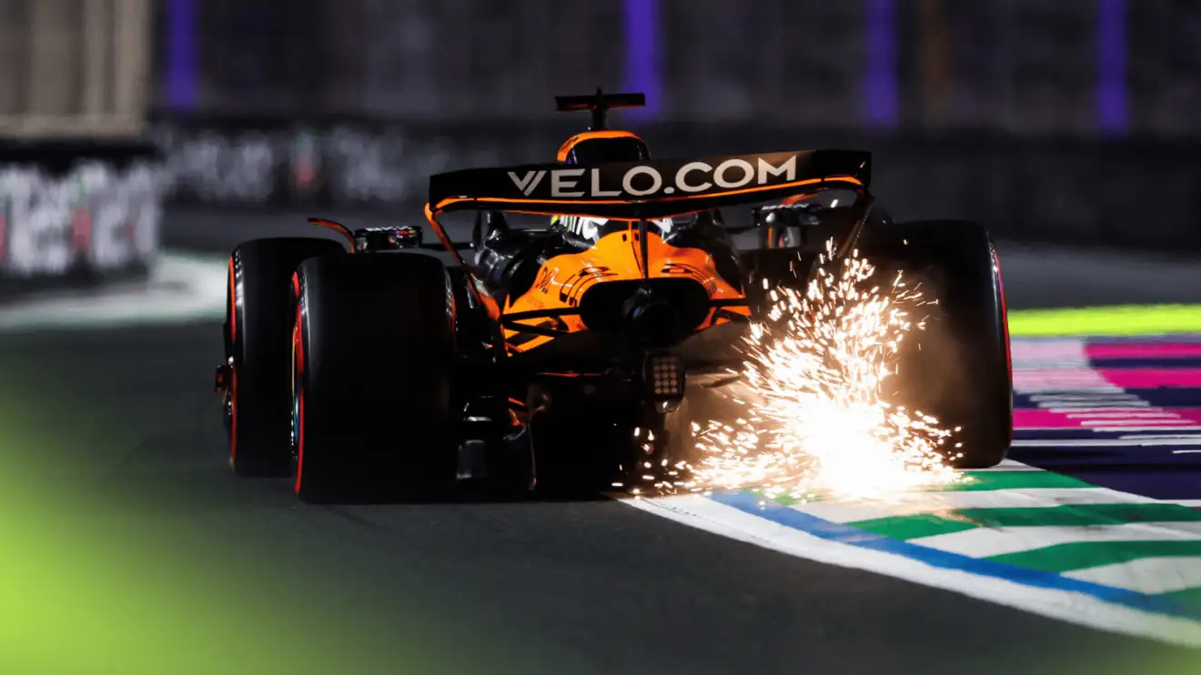 c-281 A rear-facing shot of Oscar Piastri's McLaren kicking up a shower of sparks over a kerb in Jeddah