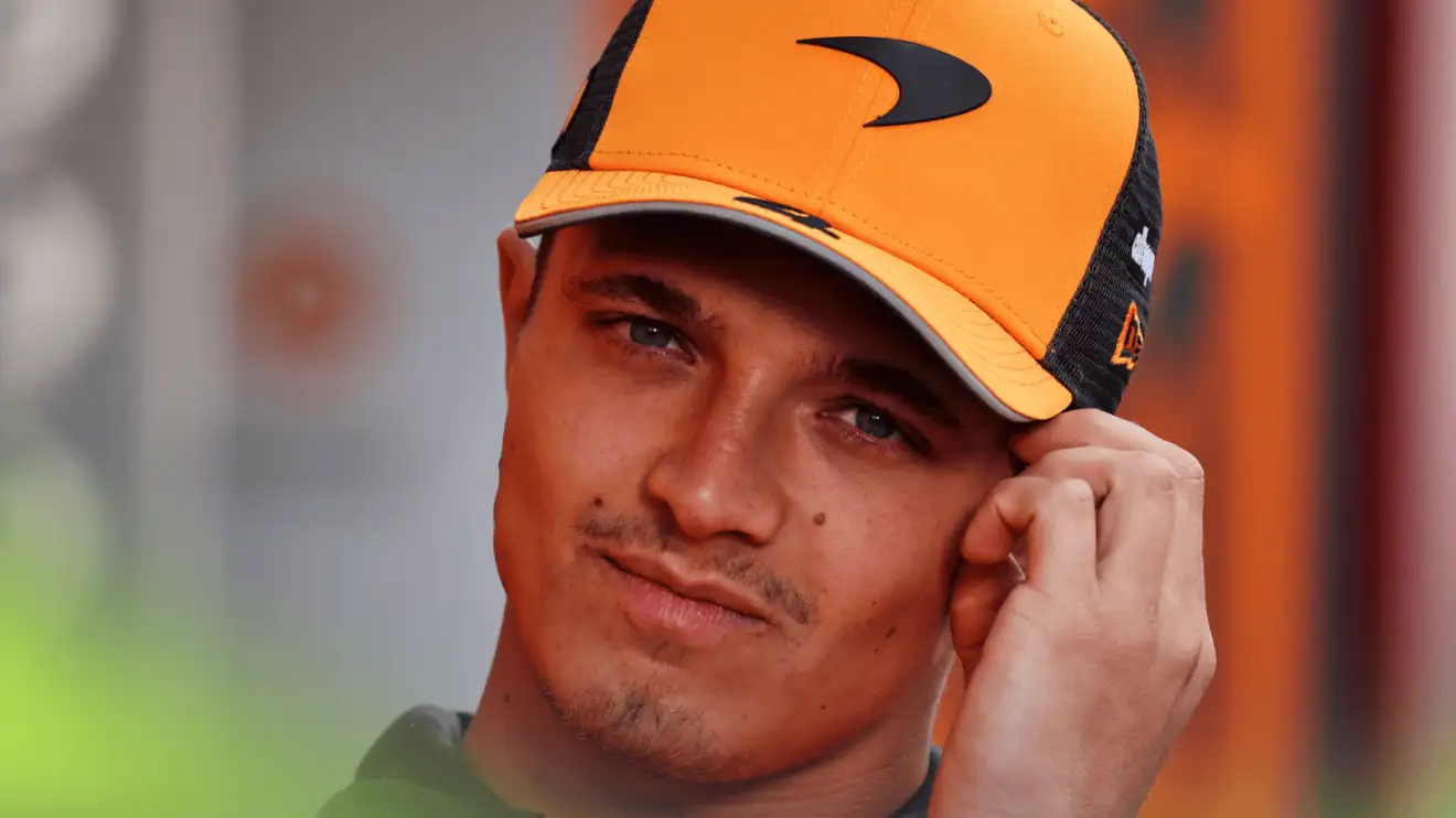 c-901 Lando Norris holds his hand to his head while wearing a McLaren cap