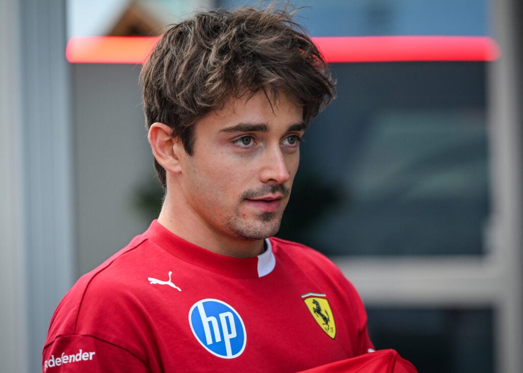 Charles Leclerc of Ferrari looks on in the F1 paddock